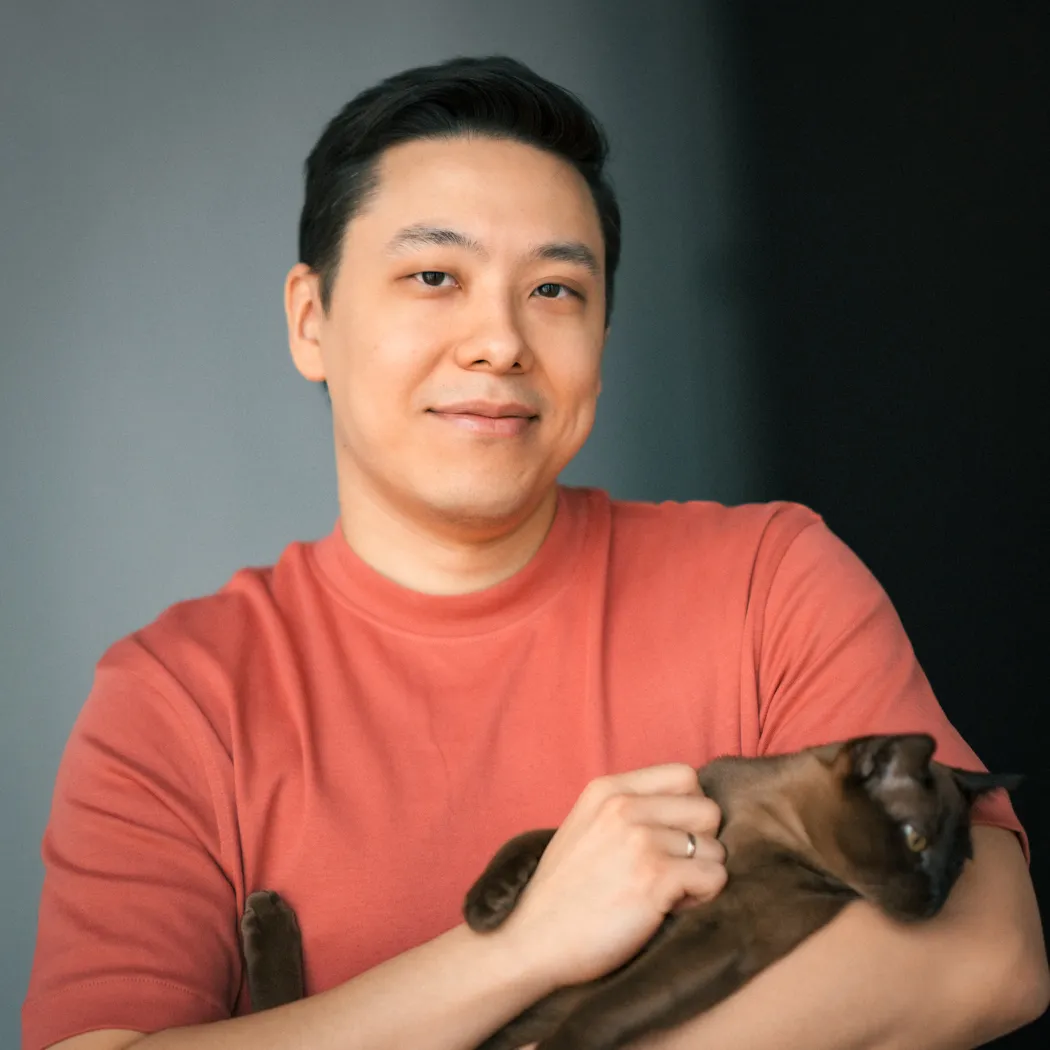 Person smiling and holding a Burmese cat